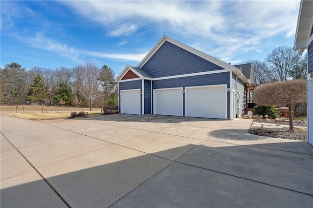 view of side of home featuring concrete driveway and a garage