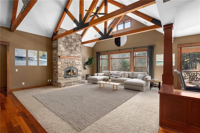 living room with beam ceiling, high vaulted ceiling, a stone fireplace, decorative columns, and baseboards