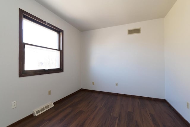 spare room featuring dark wood-type flooring, baseboards, and visible vents