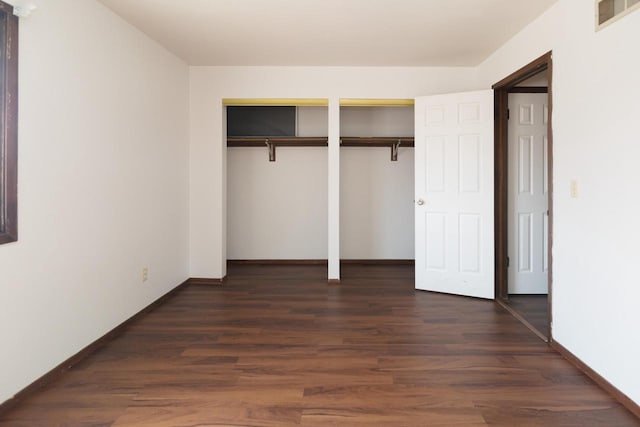 unfurnished bedroom featuring dark wood finished floors, visible vents, baseboards, and multiple closets