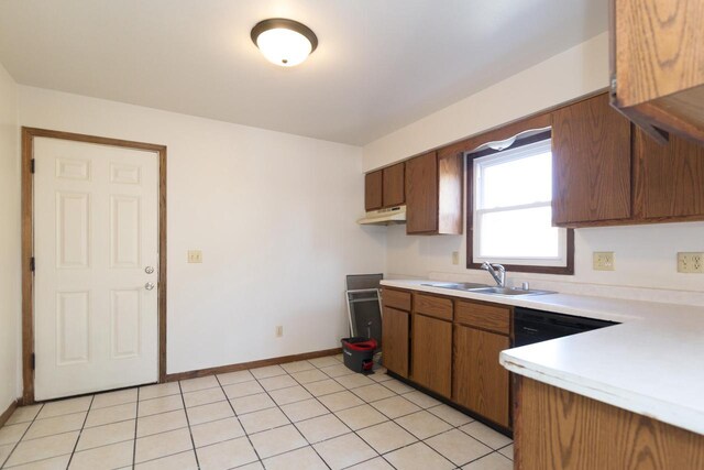 kitchen featuring baseboards, light tile patterned flooring, a sink, light countertops, and brown cabinets