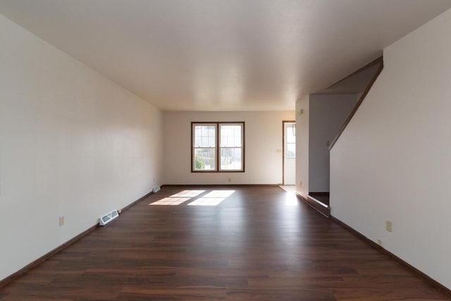 unfurnished room with visible vents, baseboards, and dark wood-type flooring