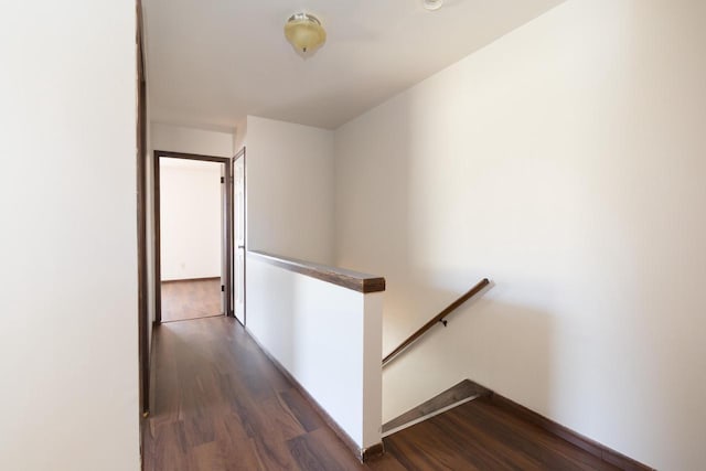 corridor with baseboards, an upstairs landing, and dark wood-style flooring