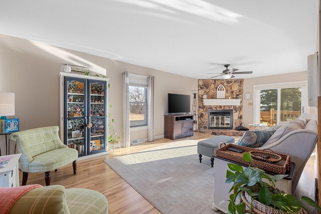 living area with a healthy amount of sunlight, ceiling fan, a fireplace, and light wood finished floors