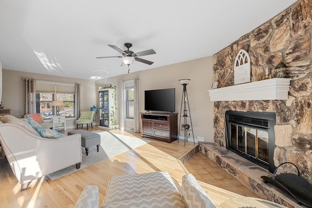 living room with a ceiling fan, light wood-style flooring, and a fireplace