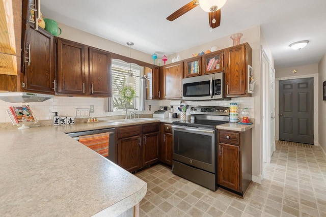 kitchen with decorative light fixtures, appliances with stainless steel finishes, light countertops, decorative backsplash, and ceiling fan