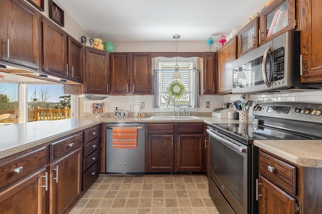 kitchen with decorative backsplash, stainless steel appliances, light countertops, and a sink