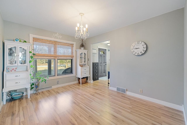 empty room featuring a chandelier, visible vents, light wood-type flooring, and baseboards