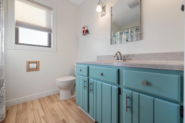 bathroom featuring baseboards, toilet, wood finished floors, and vanity