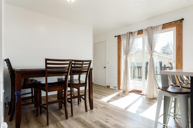 dining space featuring visible vents, light wood-style flooring, and baseboards