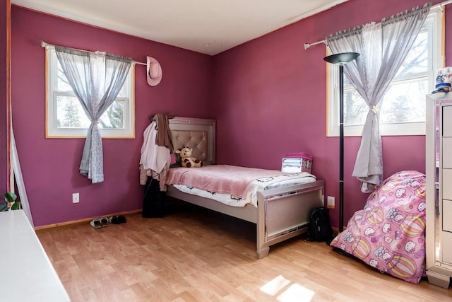 bedroom with light wood finished floors, multiple windows, and baseboards