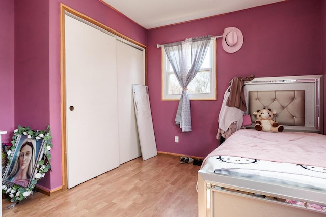 bedroom featuring a closet, light wood-type flooring, and baseboards