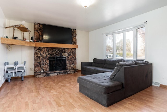 living room featuring baseboards, a fireplace, visible vents, and light wood-type flooring