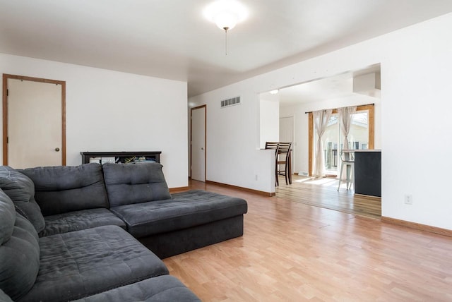 living room with visible vents, baseboards, and light wood-style flooring