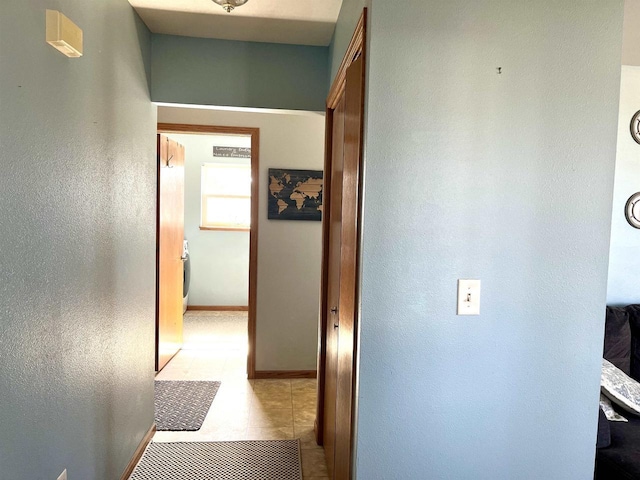 hall with light tile patterned flooring and baseboards