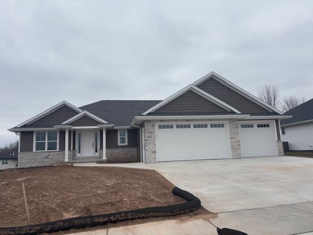 view of front of home with stone siding, driveway, and a garage