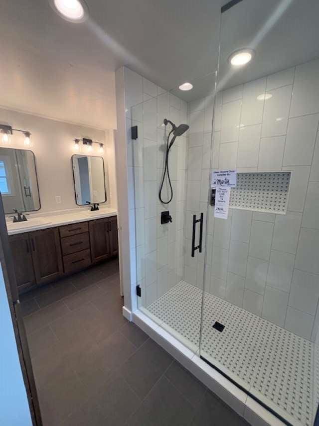 bathroom with tile patterned flooring, a stall shower, double vanity, and a sink