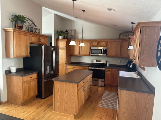 kitchen with a sink, stainless steel appliances, dark countertops, and a center island