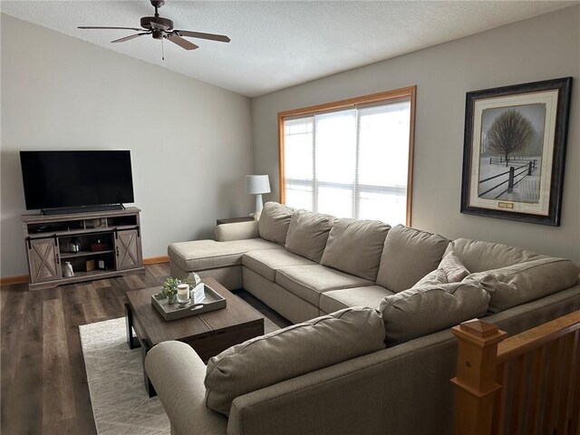 living area with dark wood finished floors, lofted ceiling, a textured ceiling, and ceiling fan