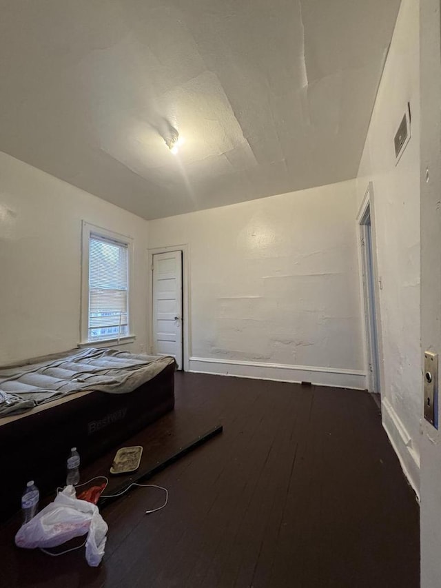 unfurnished bedroom featuring dark wood finished floors, visible vents, and baseboards