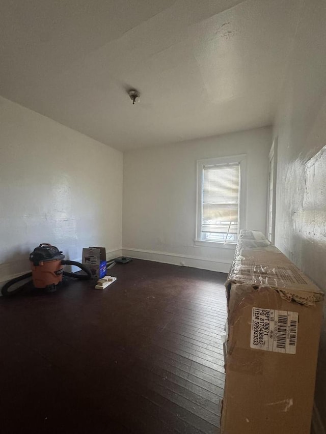 unfurnished room with dark wood finished floors and baseboards