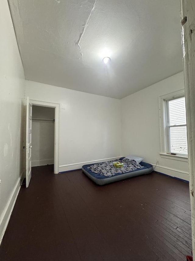 unfurnished bedroom with dark wood-type flooring and baseboards