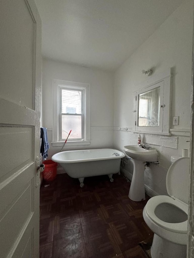 full bathroom with a wainscoted wall, a freestanding bath, toilet, and a sink