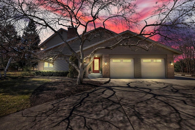 view of front of home featuring a chimney, a garage, concrete driveway, and brick siding