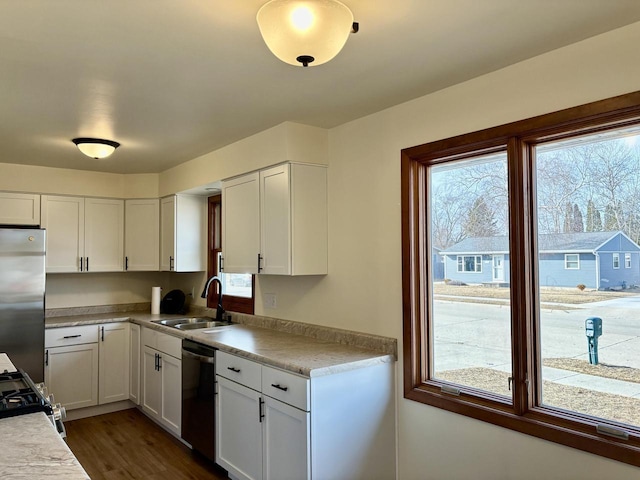 kitchen with dark wood finished floors, a sink, light countertops, appliances with stainless steel finishes, and white cabinetry