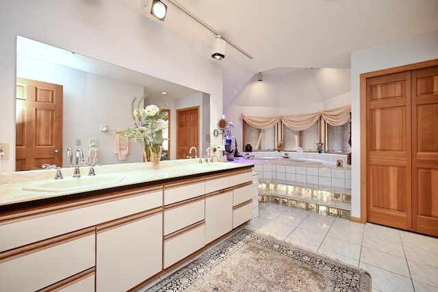 bathroom with a sink, a relaxing tiled tub, double vanity, and tile patterned flooring