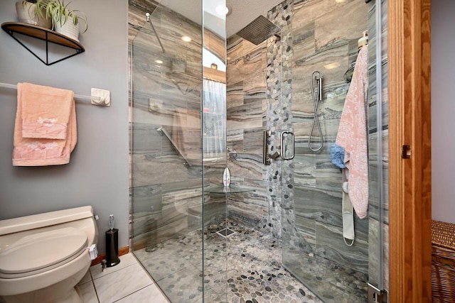 bathroom with tile patterned flooring, a shower stall, toilet, and baseboards