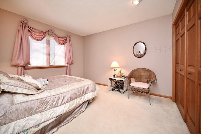 bedroom with a closet, light carpet, and baseboards