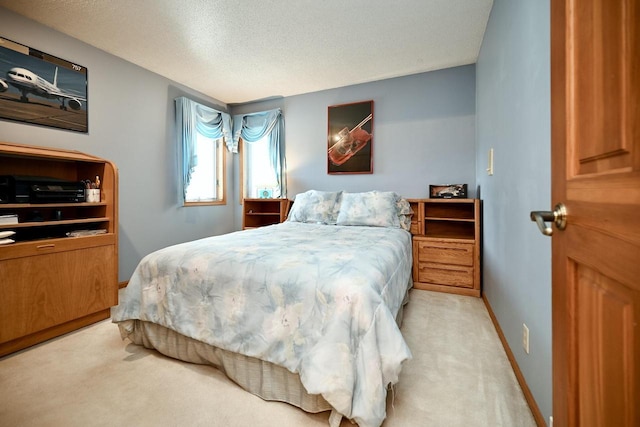 bedroom with baseboards, light colored carpet, and a textured ceiling