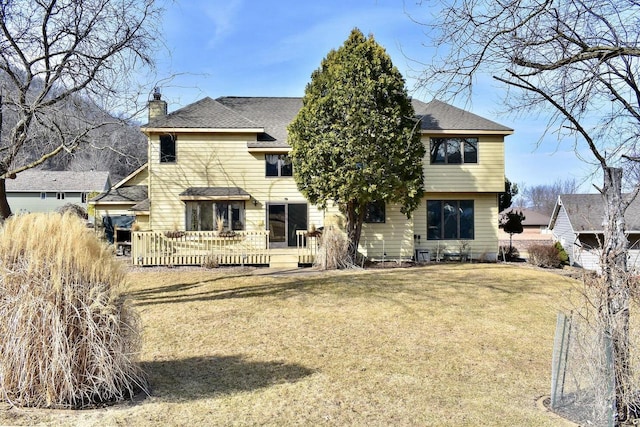 back of house featuring a wooden deck, a lawn, roof with shingles, and a chimney