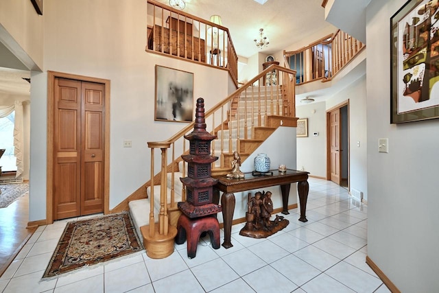 stairs featuring tile patterned floors, baseboards, and a towering ceiling