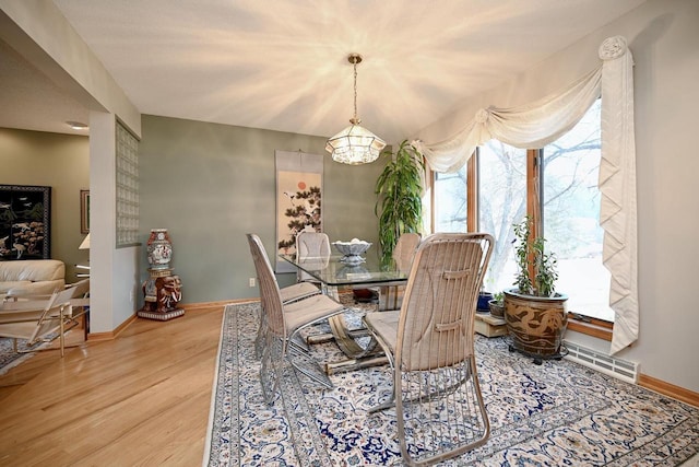 dining area with a notable chandelier, visible vents, baseboards, and wood finished floors