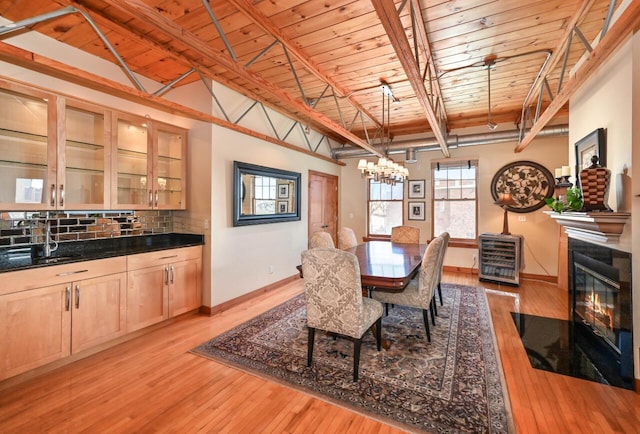 dining area with heating unit, light wood finished floors, a fireplace with flush hearth, wood ceiling, and a notable chandelier