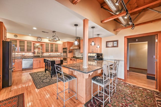 kitchen with a kitchen bar, decorative backsplash, light wood-style flooring, and appliances with stainless steel finishes