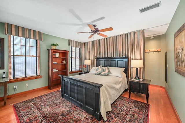 bedroom featuring an accent wall, wood finished floors, visible vents, and baseboards