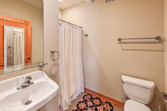 full bath with visible vents, toilet, a shower with curtain, a sink, and baseboards