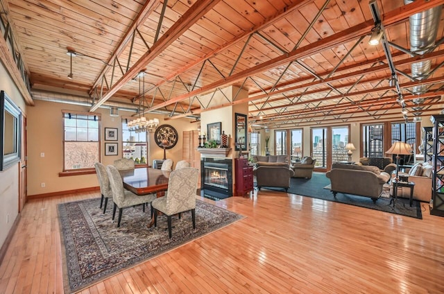 dining room with a fireplace with flush hearth, hardwood / wood-style flooring, wooden ceiling, baseboards, and vaulted ceiling