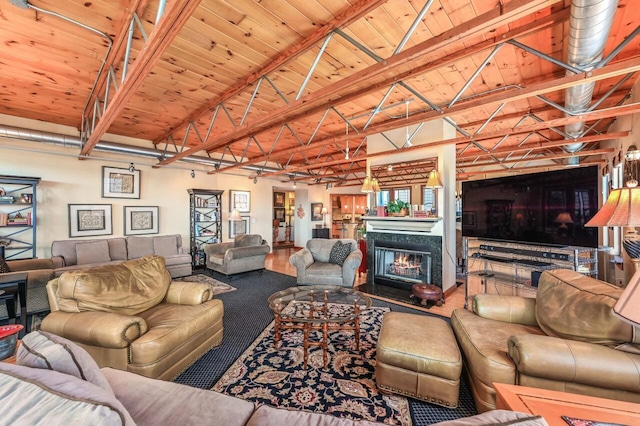 living room with vaulted ceiling with beams, a warm lit fireplace, and wood ceiling