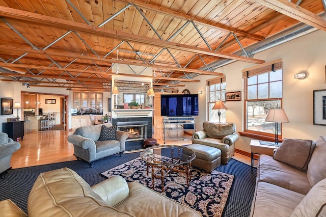 living area featuring wooden ceiling, wood finished floors, a wealth of natural light, and beam ceiling