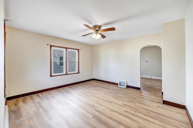 unfurnished room featuring visible vents, a ceiling fan, arched walkways, light wood-style floors, and baseboards