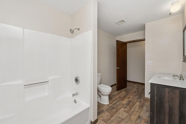 full bathroom featuring visible vents, shower / washtub combination, toilet, wood finished floors, and vanity