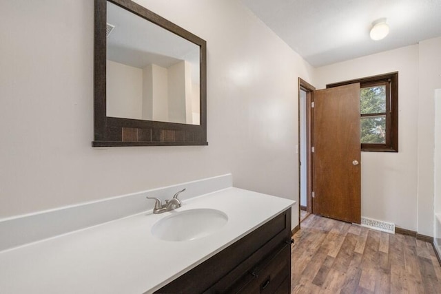 full bathroom featuring visible vents, a tub to relax in, wood finished floors, baseboards, and vanity