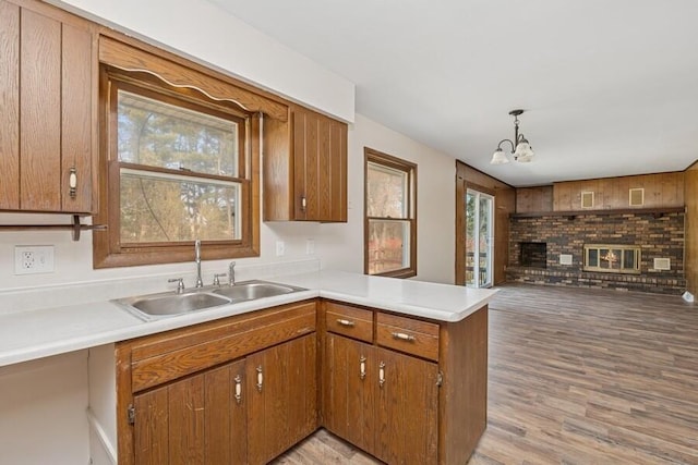 kitchen with a sink, brown cabinets, a peninsula, and light countertops