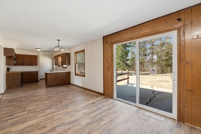 kitchen featuring wood finished floors, baseboards, a peninsula, light countertops, and a chandelier