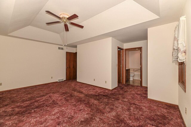 unfurnished bedroom featuring carpet flooring, baseboards, a raised ceiling, and visible vents