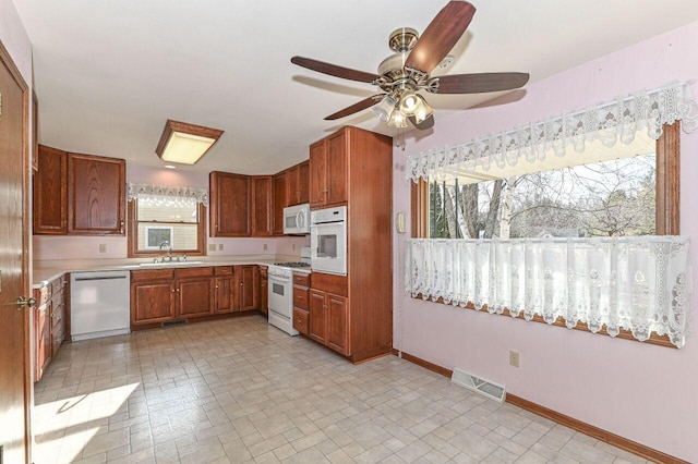 kitchen with visible vents, a ceiling fan, a sink, white appliances, and baseboards